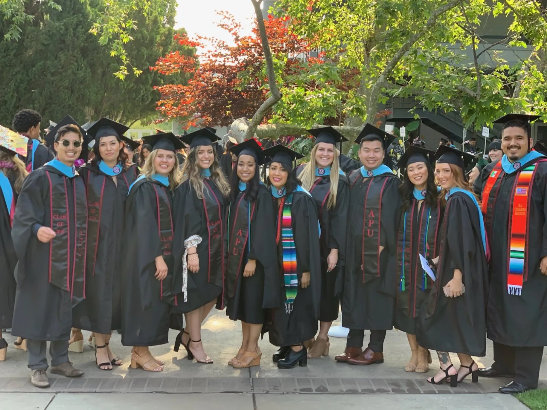 The graduating cohort of 2019 stands together outside after commencement.