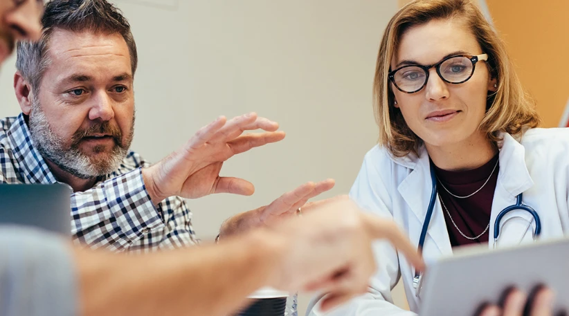 doctor showing something on an ipad to man with a beard