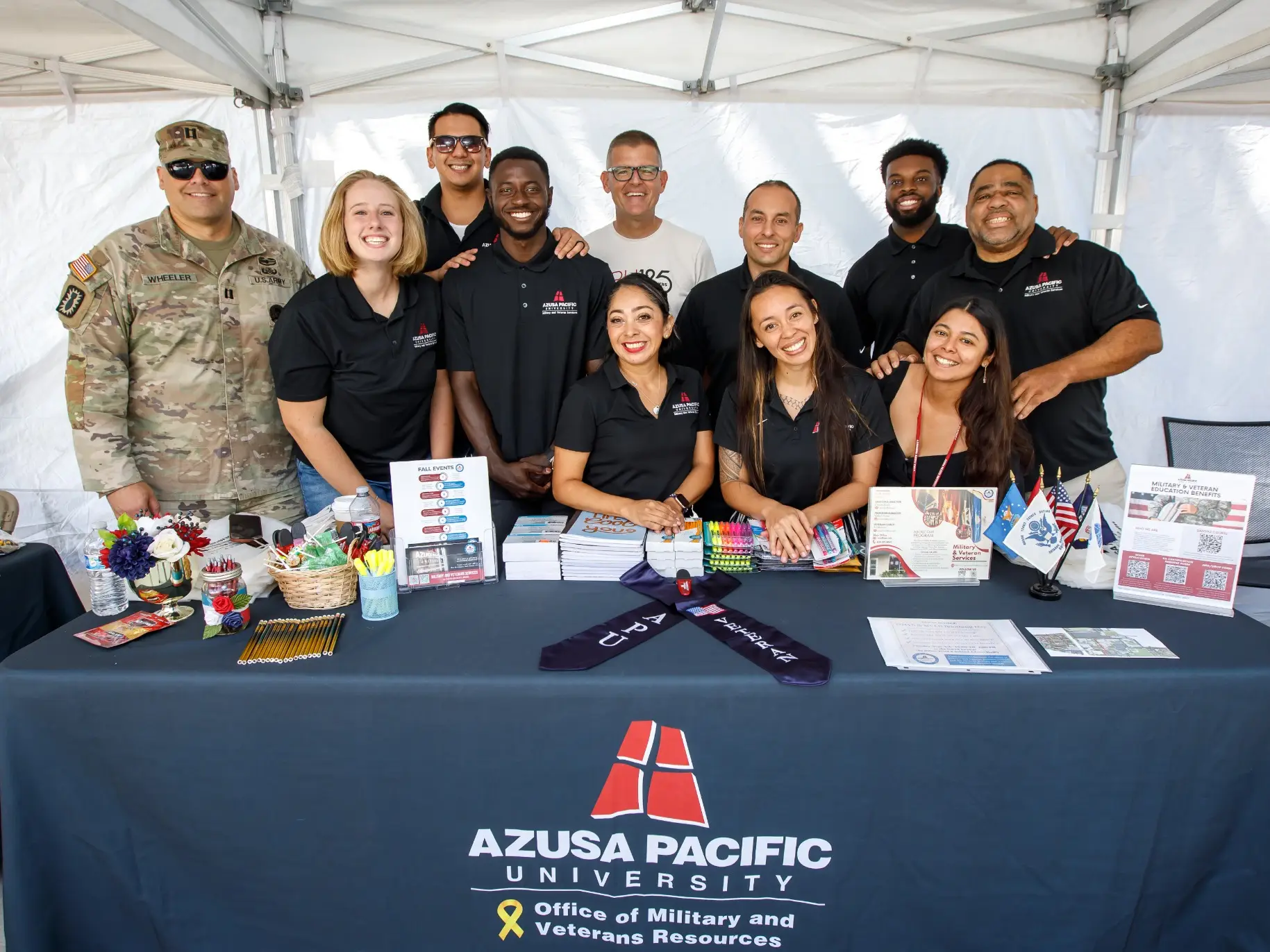 A group of military and veteran students and staff smiles with President Morris